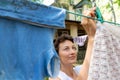 Candid real life portrait of young adult beautiful attractive caucasian woman hanging up fresh washed family clothes on Royalty Free Stock Photo