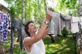 Candid real life portrait of young adult beautiful attractive caucasian woman hanging up fresh washed family clothes on birch tree Royalty Free Stock Photo