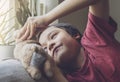 Candid short cheerful kid lying head down on sofa playing with dog toy, Child boy with haapy face playing with his soft toy or