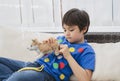 Candid short cheerful kid siting on sofa playing with dog toy, Child boy with happy face playing with his soft toy or relaxing at Royalty Free Stock Photo