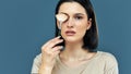 Candid studio portrait of a happy brunette young woman looking to the camera and making makeup with a brush herself Royalty Free Stock Photo