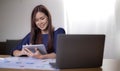 Candid young smiley Asian woman sitting at desk working online on her laptop computer. Businesswoman typing on computer Royalty Free Stock Photo