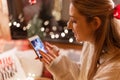 Candid young woman holding in hands smartphone and looking or viewing photos on display. enjoyment relaxing at camping home in coz Royalty Free Stock Photo