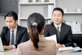 Candidate woman from behind having interview for new job by two businessman managers, giving CV resume to human resources officer Royalty Free Stock Photo