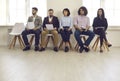 Candidates with resumes in their hands sit on chairs in the lobby waiting for an interview. Royalty Free Stock Photo