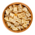 Candied ginger root cubes in wooden bowl over white