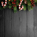 Candies, fir branch, cones and and red berries on black wood background