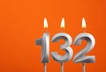 132 candle - Birthday celebration on orange background Royalty Free Stock Photo