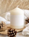 Candle with blank label near pine cones and sweater, Close up, copy space, mock up