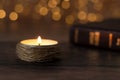 Candle burning with bright flame and closed holy bible book on wooden table with bokeh background Royalty Free Stock Photo