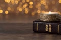 Candle burning and closed holy bible book on wooden table with bokeh background Royalty Free Stock Photo