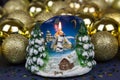 Candle burning in the form of stacked birch logs with a house moon snow-covered Christmas trees on the background of Golden balls. Royalty Free Stock Photo