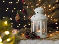 Candle in christmas lantern with fir branch, pine cones and baubles with blurred decorated christmas tree and bokeh lights Royalty Free Stock Photo