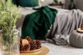 Spruce candle and cone on small wooden table in grey and emerald green bedroom interior Royalty Free Stock Photo