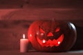 Candle and a creepy smiling Halloween pumpkin on a wooden table