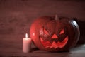 Candle and a creepy smiling Halloween pumpkin on a wooden table