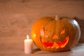 Candle and a creepy smiling Halloween pumpkin on a wooden table