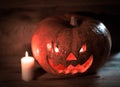 Candle and a creepy smiling Halloween pumpkin on a wooden table
