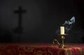 Candle on a dark background with the silhouette of the cross.