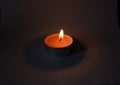 Candle on dark luxury night background. Black table, side view. Candles Burning at Night. Orange taper burning in focus,