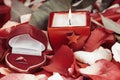 candle and a diamond ring on a background of rose petals