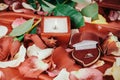 Candle and a diamond ring on a background of rose petals