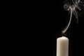 Candle with extinguished flame in front of black background