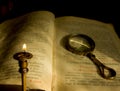 A dying candle and an old prayer book with a magnifying glass Royalty Free Stock Photo