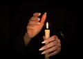 Candle and female witch hands with sharp pearl nails. Divination and witchcraft, low key. Royalty Free Stock Photo
