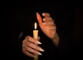 Candle and female witch hands with sharp pearl nails. Divination and witchcraft, low key. Royalty Free Stock Photo