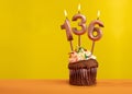 Candle with flame number 136 - Birthday card on yellow background