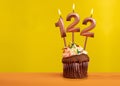 Candle with flame number 122 - Birthday card on yellow background