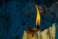 The candle flame on the yellow candle with the dirty old blue plastic backdrop Royalty Free Stock Photo