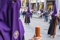 The candle in flame of a young Nazarene with a rosary to pray in her hands, doing his penance station in the Holy Week procession