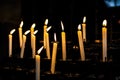 Candle flames in the Christian church. Group of yellow candles at the church. Dark mood with burnt candles. Royalty Free Stock Photo