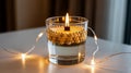 Candle floating in glass with beads and string lights on white surface Royalty Free Stock Photo