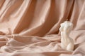 Candle in the form of a female figure on a white fabric background