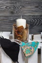 A candle in a glass candlestick. The candlestick is filled with dried cones, spices and dried fruits. Stands on a wooden box.