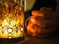 Candle and hands folded together in prayer or petition Royalty Free Stock Photo