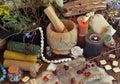 Candle, herbs, rune and books on witch altar table.