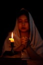 Candle light with blur young girl praying in dark night background. Woman person worship God with faith and belief. religion, Royalty Free Stock Photo