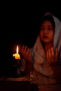 Candle light with blur young girl praying in dark night background. Woman person worship God with faith and belief. religion, Royalty Free Stock Photo