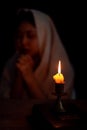 Candle light with blur young girl praying in dark night background. Woman person worship God with faith and belief. religion, Royalty Free Stock Photo