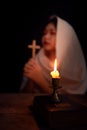 Candle light with blur young girl praying in dark night background. Woman person worship God with faith and belief. religion, Royalty Free Stock Photo