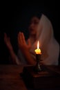 Candle light with blur young girl praying in dark night background. Woman person worship God with faith and belief. religion, Royalty Free Stock Photo