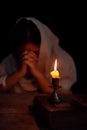 Candle light with blur young girl praying in dark night background. Woman person worship God with faith and belief. religion, Royalty Free Stock Photo