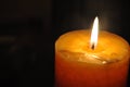 Candle light an the dark night. Yellow, orange candle burning, yellow flames and dark, black background