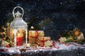 Candle light lantern and Christmas decoration in the snow against a dark blue wooden background with copy space Royalty Free Stock Photo