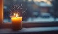 A candle is lit in front of a window with snow outside Royalty Free Stock Photo