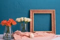 A candle is lit on the table next to a picture frame and a vase with rose flowers on a blue background Royalty Free Stock Photo